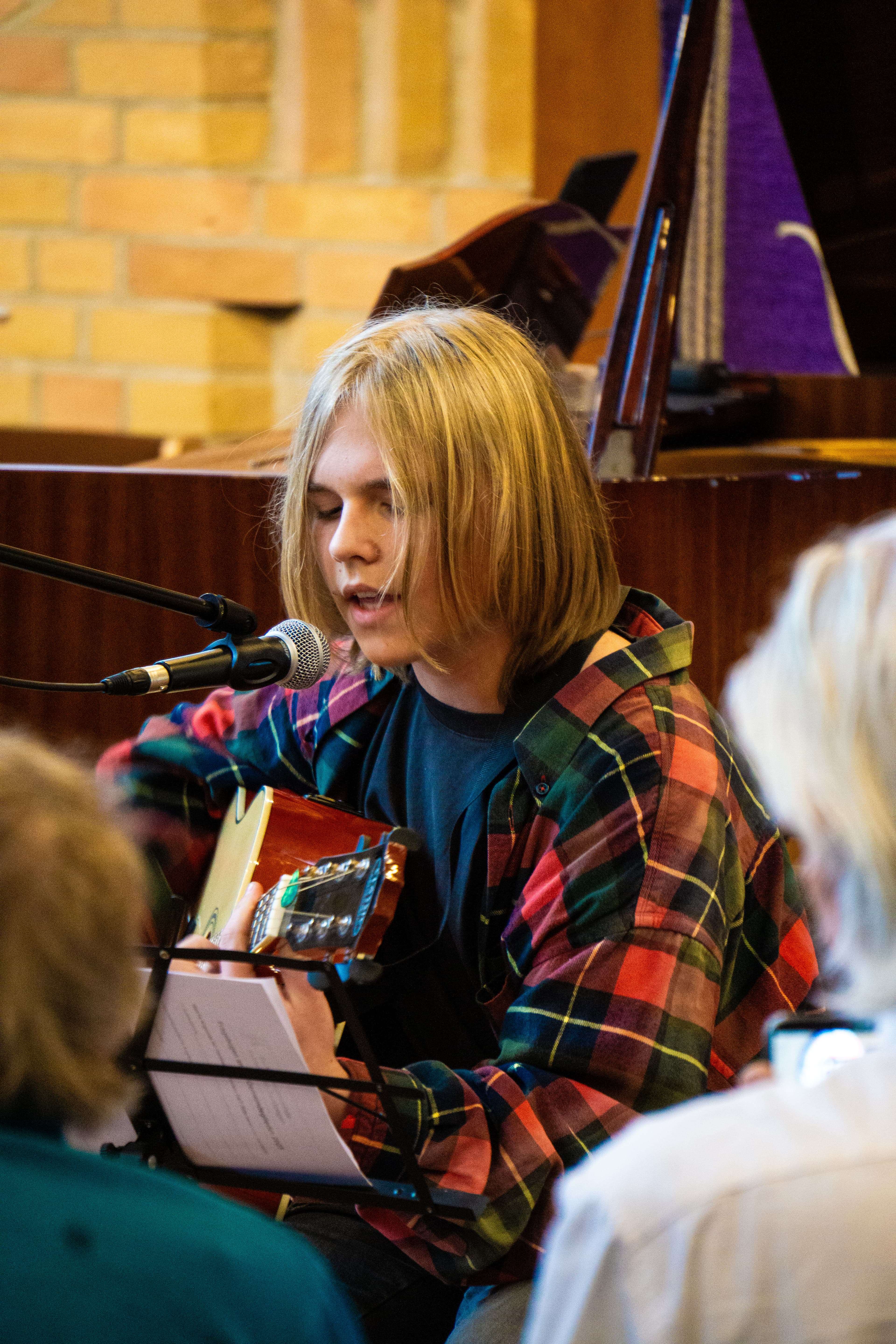 Eine junge Sängerin von Musik integriert e.V. singt bei einem Benefizkonzert am Mikrofon, begleitet an der Gitarre
